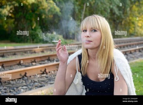 Portrait Of Woman Smoking Cigarette While Sitting Outdoors Stock Photo