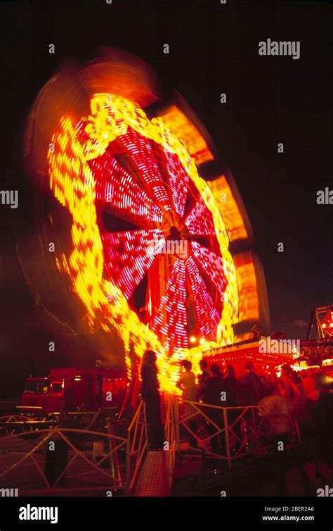 Funfair Night View Of Rotating Ferris Wheel With People Stock Photo