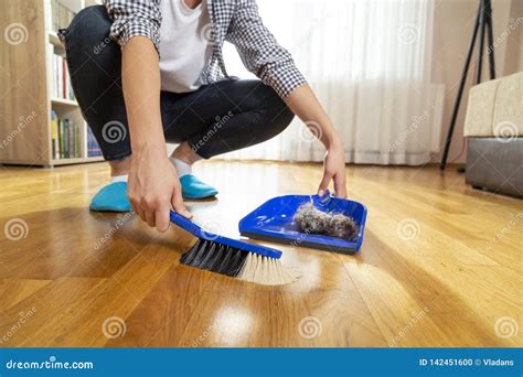 Woman Sweeping Floor And Collecting Dust Onto A Dustpan Stock Photo