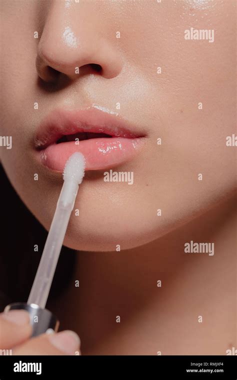 Close Up Of Woman Applying Transparent Lip Gloss With Applicator