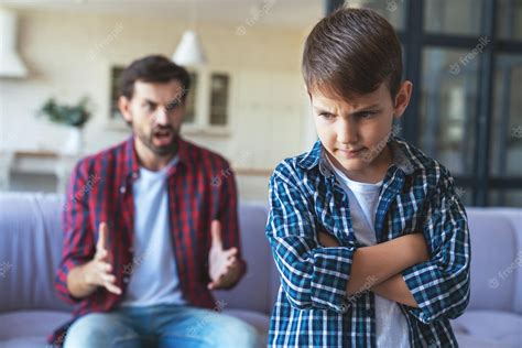 premium photo an angry father quarrels with his little son who stands offended in the