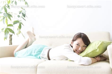 ソファで寝転ぶ女性の写真素材 24022339 イメージマート