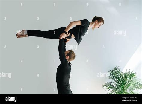 Fun Couple Doing Gymnastic Form He Is Holding Her On Strtaight Arms By