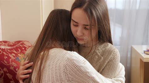 Teenage Girl Hugging And Consoling Her Crying Friend At Bedroom