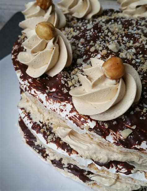 A Chocolate Cake With White Frosting And Nuts On Top