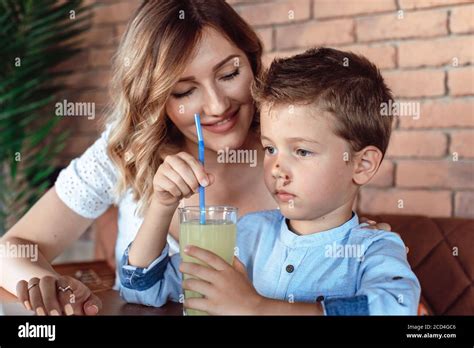 Mom Watching Over Her Son In The Cafe Son Drinking Soft Drink Stock