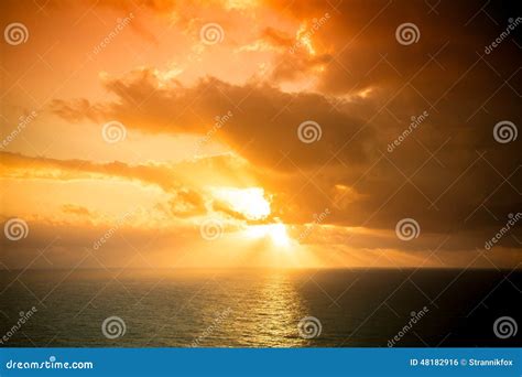 Dramatic Sunset Rays Through A Cloudy Dark Sky Over The Ocean T Stock