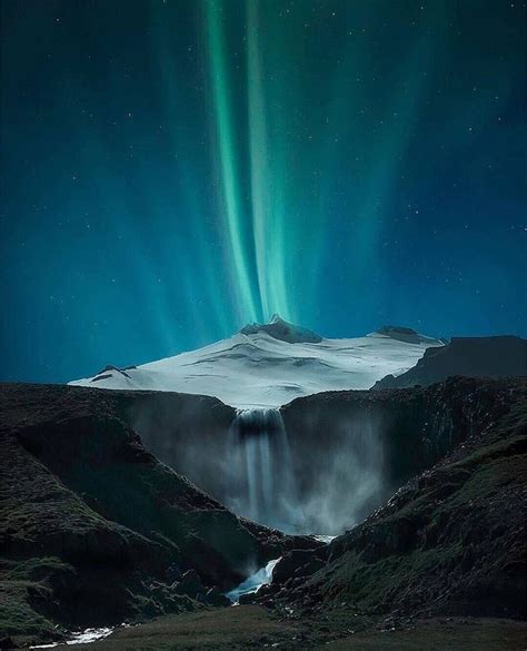 The Aurora Bore Is Shining Brightly In The Night Sky Over A Mountain