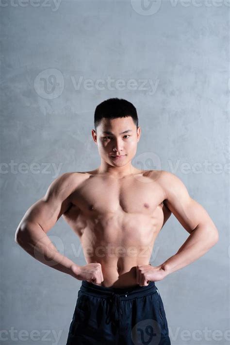 hombre asiático musculoso posando sobre fondo gris Foto de stock en Vecteezy