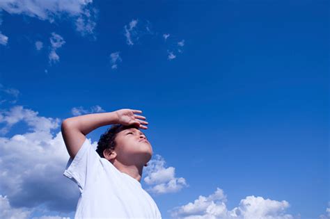 Closeup Of A Boy Looking Ahead Against A Blue Sky Stock Photo