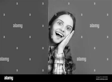shocked girl behind blank pink paper with copy space for advertisement