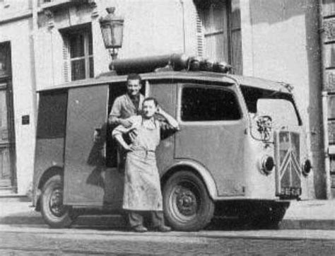 An Old Black And White Photo Of Two People Standing In Front Of A Van