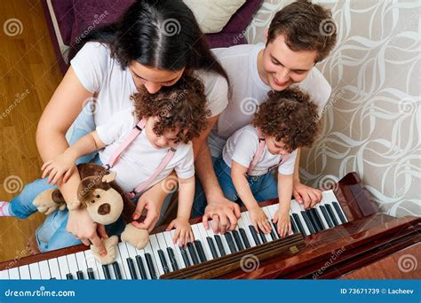 Parents With Daughters Twins Study Music At The Piano Top View Stock