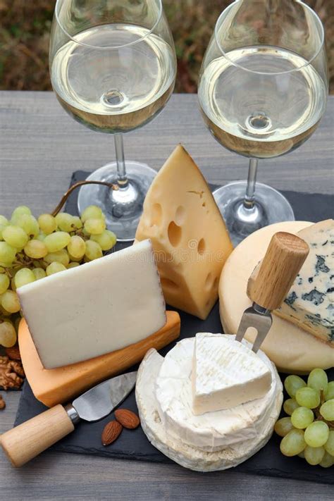 Different Types Of Delicious Cheeses Snacks And Wine On Wooden Table