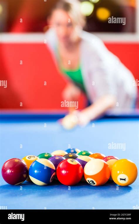 Couple Or Friends Playing Billiard With Queue And Balls On Pool Table