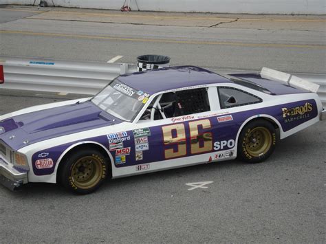 A Purple And White Race Car With Stickers On Its Side Sitting In The