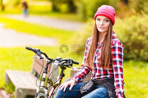 年轻女子骑着自行车在公园长凳上休息高清图片下载 正版图片304195049 摄图网