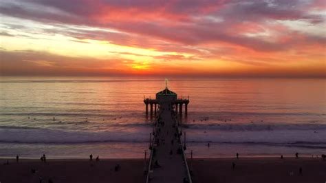 Fiery Sunset Sky In Manhattan Beach Pier With People Swimming During