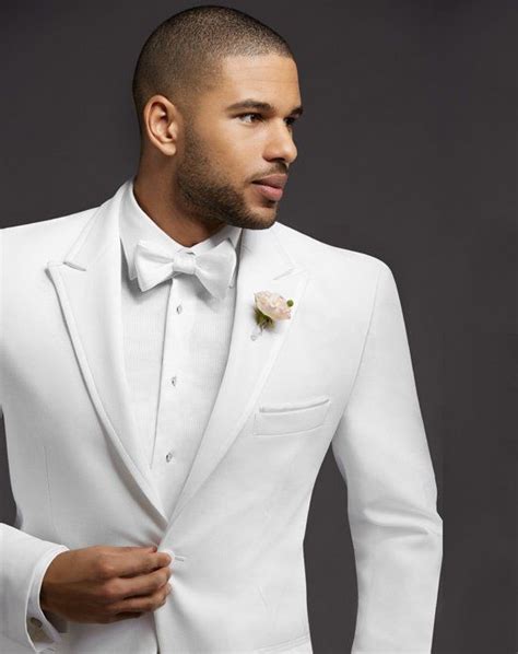 A Man In A White Tuxedo With A Flower Pinned To His Lapel