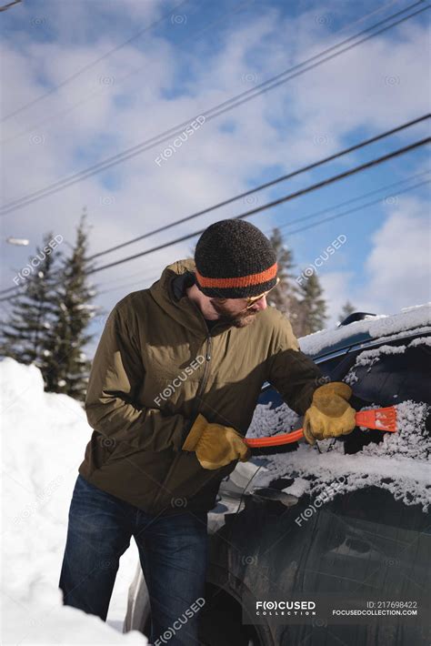 Man Cleaning Snow From Car Windshield During Winter — Warm Clothing