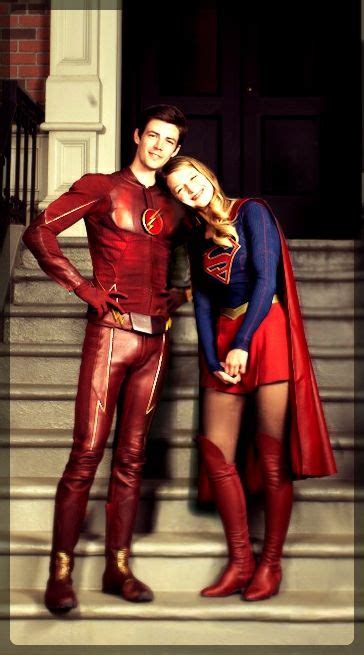 A Man And Woman Dressed Up As Superman And Flash Standing On The Steps In Front Of A Building