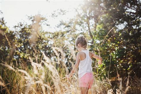 Cute Young Girl Walking In Tall Grass Exploring Nature In Summer Del Colaborador De