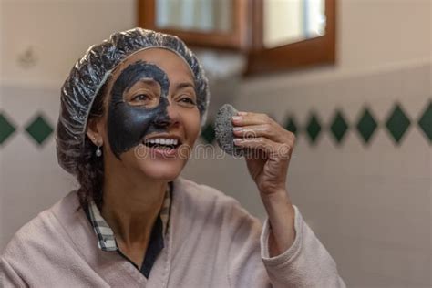 Close Up Of A Smiling Woman While Removing The Mud Mask From Her Face