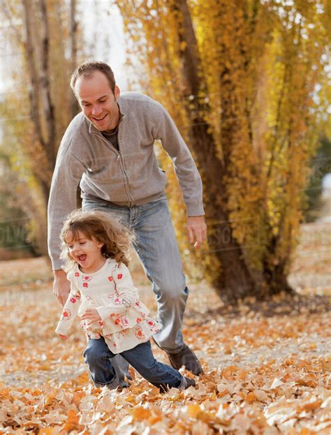 Caucasian Father And Daughter Playing In Autumn Leaves Stock Photo