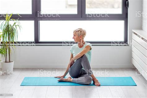 Mature Woman In Joga Pose Exercise In Appartment At Rug With Window On
