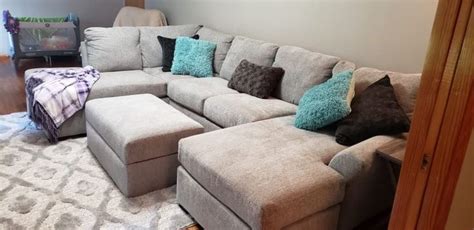 A Living Room With A Large Sectional Couch And Lots Of Pillows On Top Of It