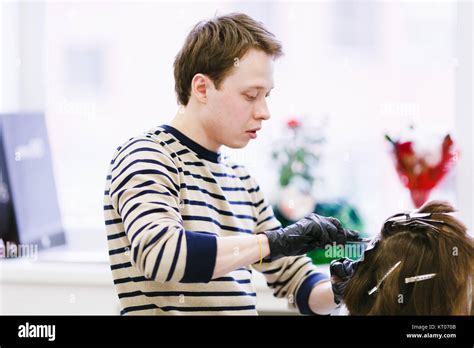 the hairdresser in the beauty salon makes hair coloring. young male