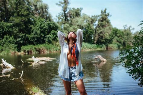 Premium Photo Sensual Sexy Brunette Girl In An Unbuttoned White Shirt To Undress Near The River