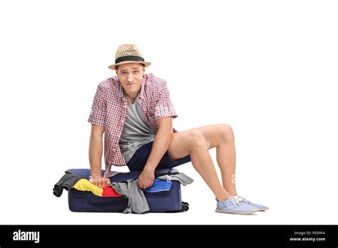 Sad Young Male Tourist Sitting On Top Of A Packed Suitcase And Trying