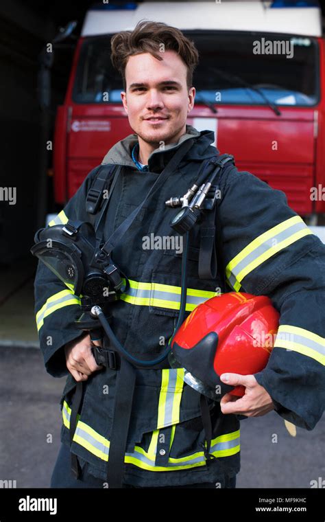 Handsome Young Fireman Holding Fire Hose In Uniform Stock Photo Alamy