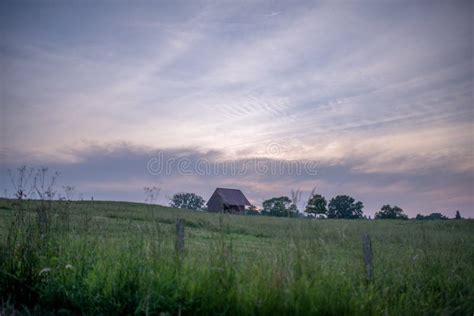 Old Farmhouse In The Countryside At Sunset With Some Clouds In The Sky