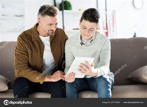père adolescent fils utilisant tablette assis sur canapé maison image libre de droit par