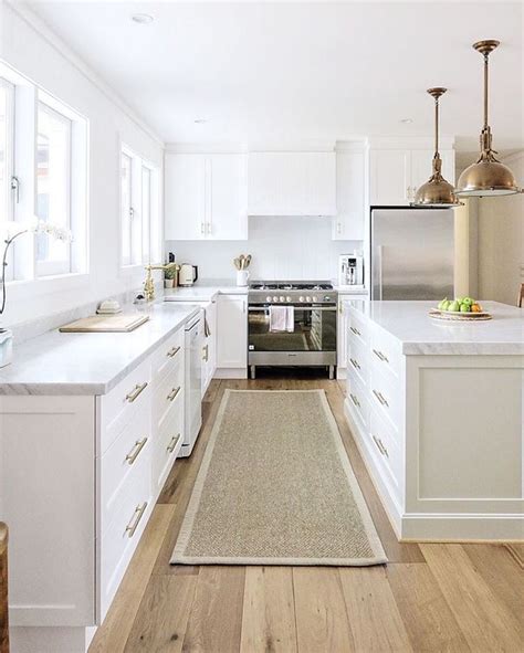 Since the entire living, dining and kitchen area uses the same flooring, the kitchen island creates a natural partition. Sisal runner, white kitchen with carrara marble, brass ...