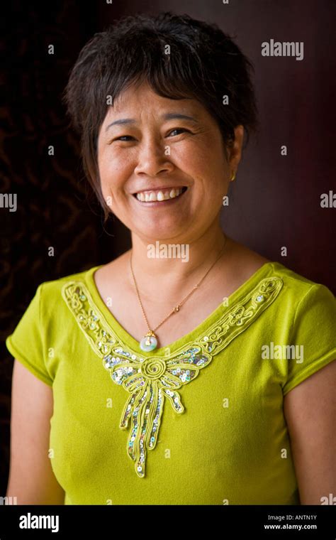 Middle Aged Asian Oriental Chinese Woman In Yellow Dress Smiling