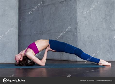 Side View Of Skinny Young Yogini Standing In Yoga Backbend Pose On Mat