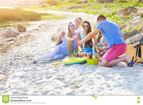 Friends Sitting On The Sand At The Beach At The Summer Picnic Stock