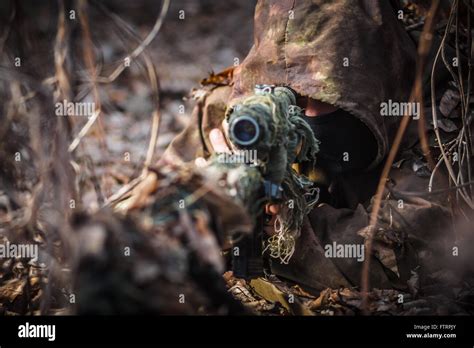 Sniper Wearing Camouflage Suit With Rifle Hide In The Woods Stock Photo
