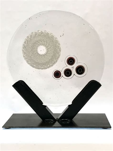 A Glass Sculpture With Four Black And White Circles On It S Base In Front Of A White Background