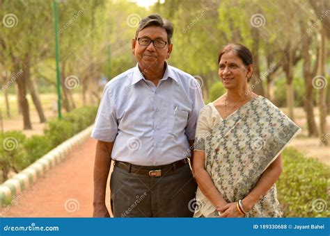 happy looking retired senior indian man and woman couple smiling and posing in a park outdoor