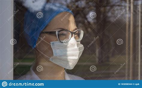 tired doctor looks at window female medical worker in eyeglasses and protective mask looks