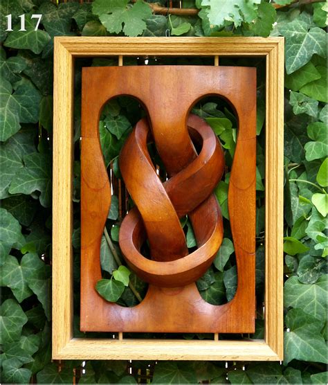 An Art Piece Made Out Of Wood With Green Leaves Around It And In The Frame