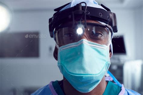 Portrait Of Male Surgeon Wearing Protective Glasses And Head Light In