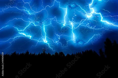 Lightning Strike On A Dark Blue Sky Over The Forest Silhouette Photo