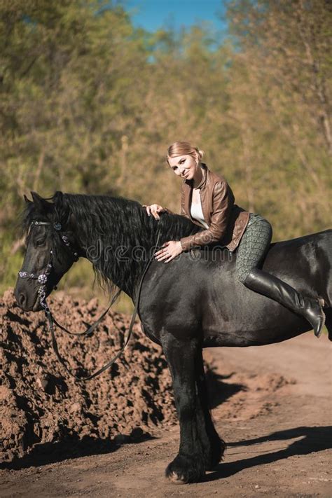 Brunette Woman Riding Dark Horse At Summer Green Forest Stock Image