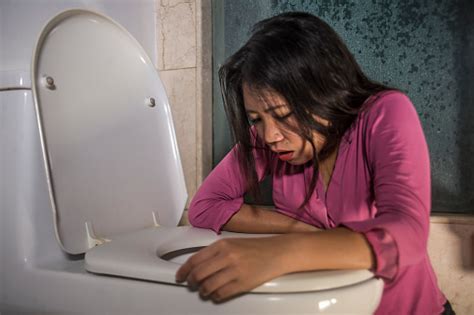 Young Drunk Or Pregnant Asian Woman Vomiting And Throwing Up In Toilet