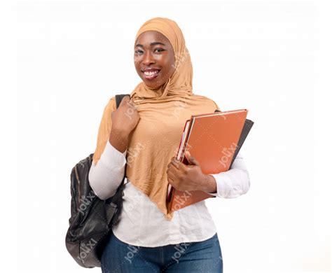 Jeune étudiante musulmane africaine voilée souriante avec son sac à dos tenant ses cahiers sur